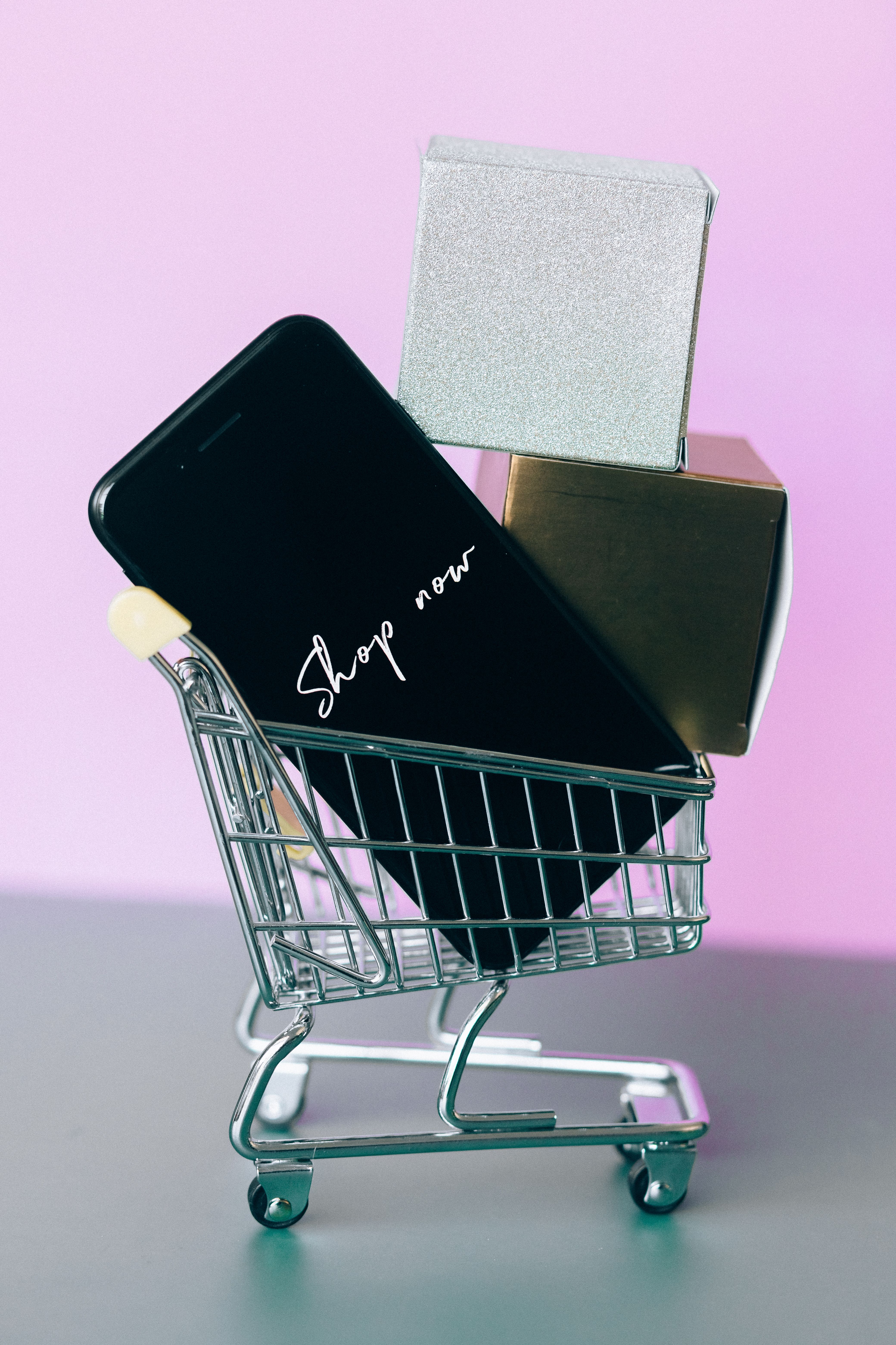 Smartphone affichant Shop now dans un mini caddie de course rose
